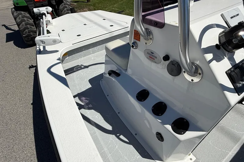 Slide: The Image of 2022 Majek 18 M2 boat interior with steering console and seating, parked on pavement. - 12