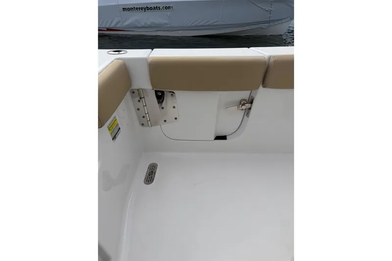 Slide: The Image of 2017 Sportsman Heritage 251 Center Console boat interior with beige seating and storage compartment. - 15