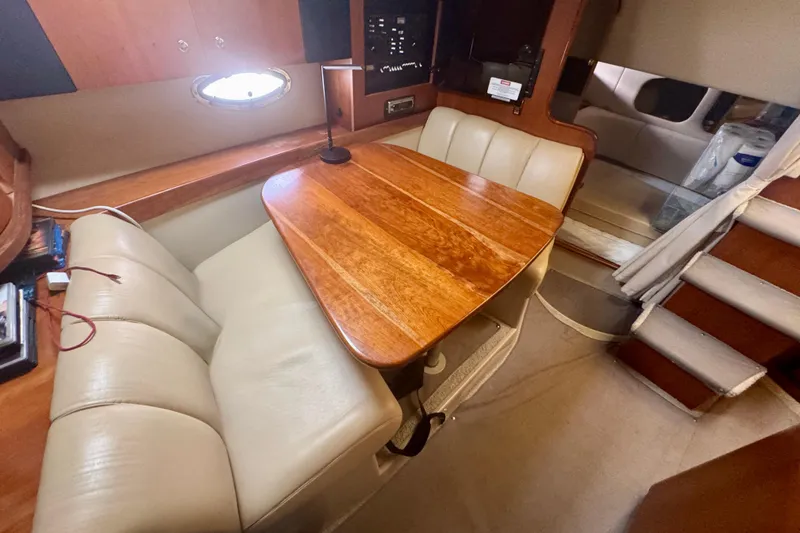 Slide: The Image of Interior of 2001 Cruisers Yachts 3470 Express with wooden table and beige seating. - 14