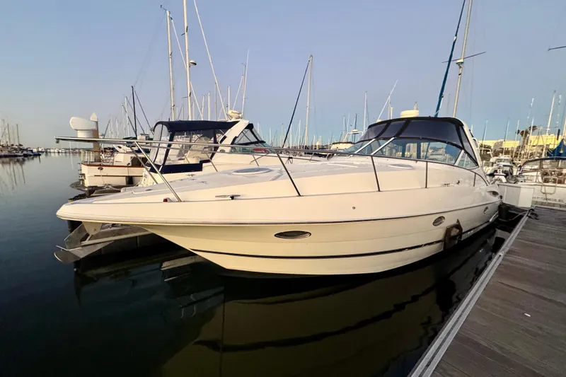 Slide: The Image of 2001 Cruisers Yachts 3470 Express docked in a marina, surrounded by sailboats. - 2
