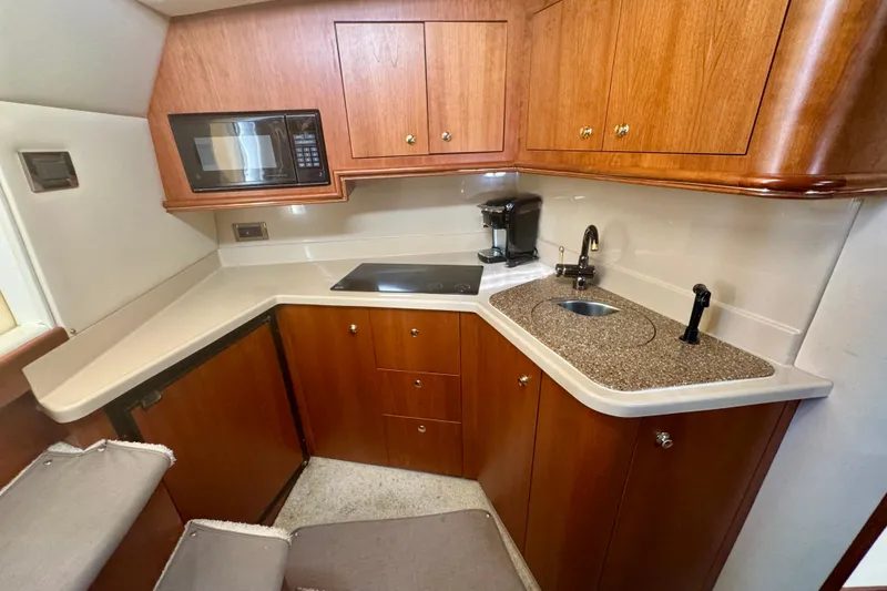 Slide: The Image of 2001 Cruisers Yachts 3470 Express kitchen with microwave, stove, sink, and wooden cabinetry. - 20