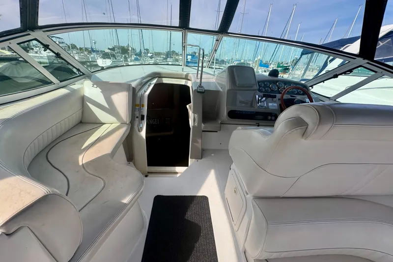 Slide: The Image of 2001 Cruisers Yachts 3470 Express cockpit with white seating and helm, docked at marina. - 31