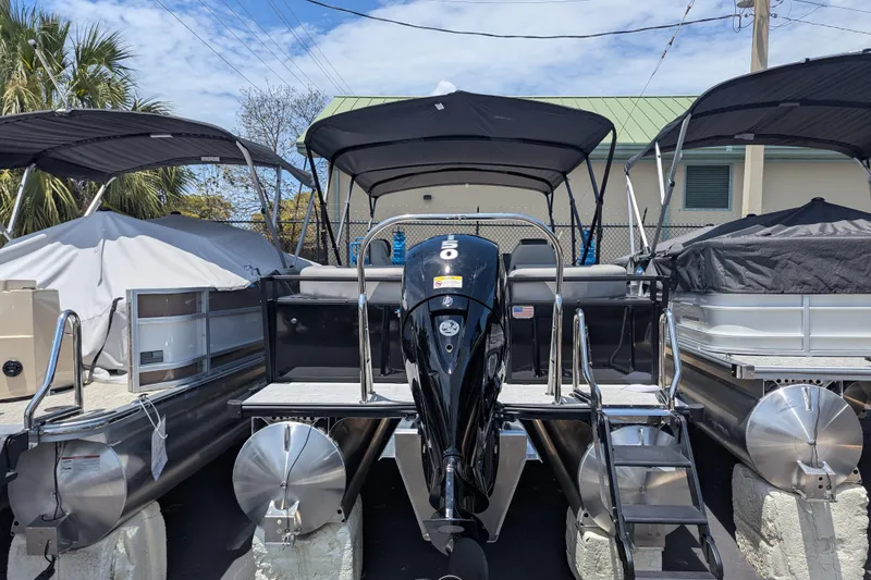 Slide: The Image of 2026 Dockside 22DQ2.75 pontoon boat with outboard motor, docked under canopy. - 11