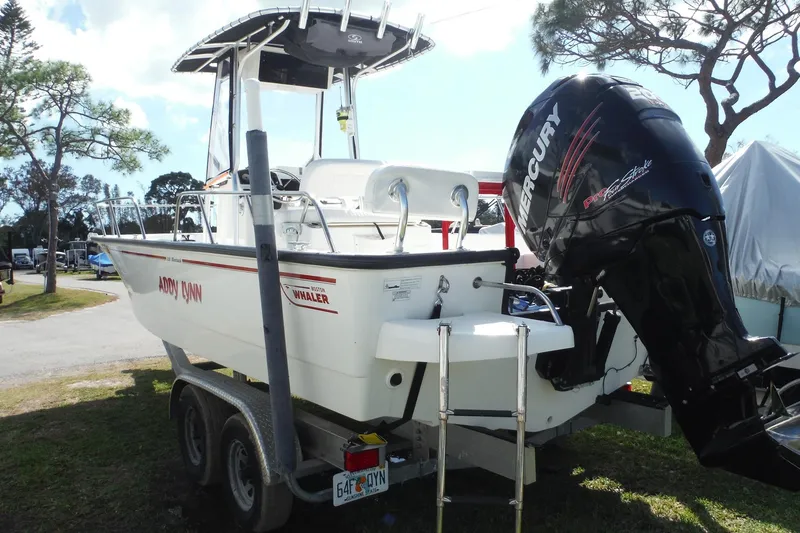 Slide: The Image of 2015 Boston Whaler 210 Montauk boat on trailer with Mercury engine, parked outdoors. - 7