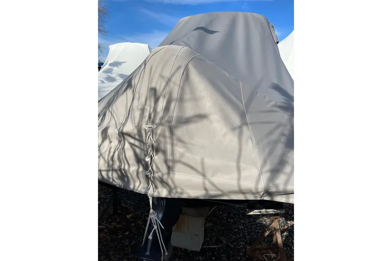Slide: The Image of 2023 Grady-White Adventure 218 boat covered with a protective tarp, outdoors. - 13