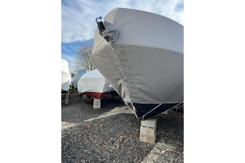 Slide: The Image of 2023 Grady-White Adventure 218 boat covered and stored on blocks outdoors. - 21