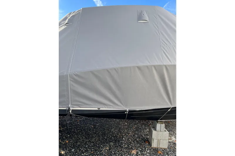 Slide: The Image of Covered 2023 Grady-White Adventure 218 boat on gravel, secured with cinder blocks. - 22