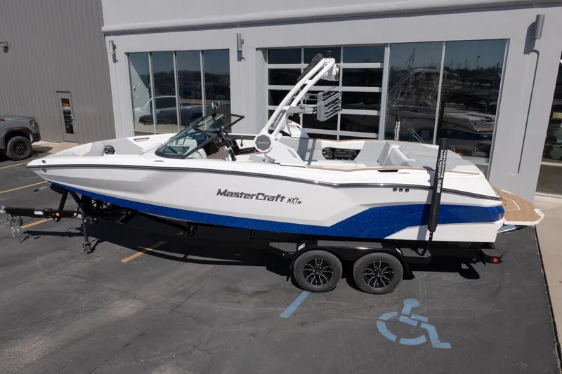 Slide: The Image of 2026 MasterCraft NXT24 boat on trailer outside dealership. - 2