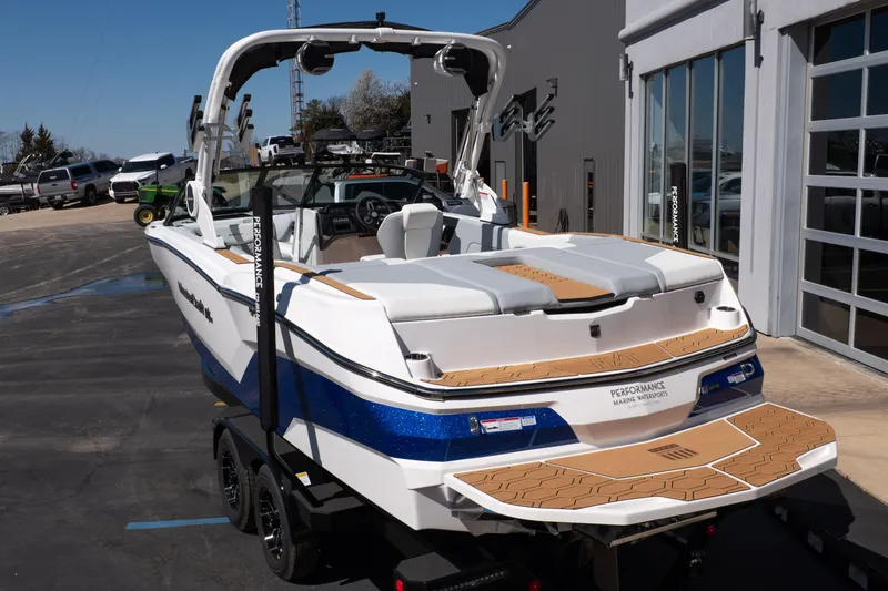 Slide: The Image of 2026 MasterCraft NXT24 boat with blue accents, parked outside a showroom. - 5