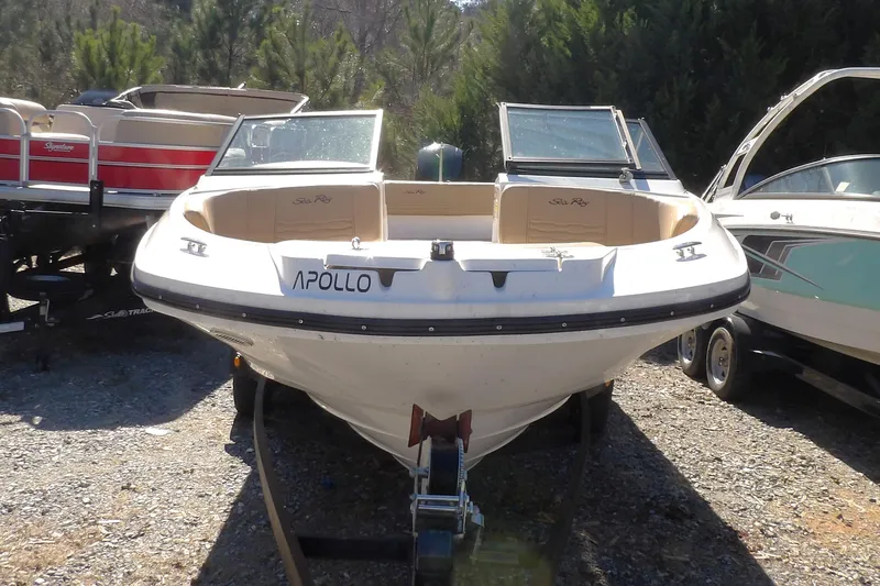 Slide: The Image of 2023 Searay 210 SPO boat named Apollo, parked on gravel with trees in background. - 1