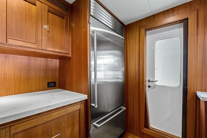 Slide: The Image of Luxurious Marlow 90 V yacht interior with wood cabinetry and modern stainless steel refrigerator, 2024 model. - 22