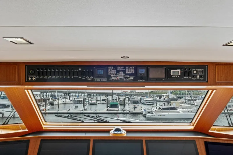 Slide: The Image of Control panel of 2024 Marlow 90 V yacht overlooking marina with docked boats. - 65