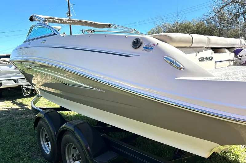 Slide: The Image of 2009 Sea Ray 210 boat on trailer, side view under clear blue sky. - 10
