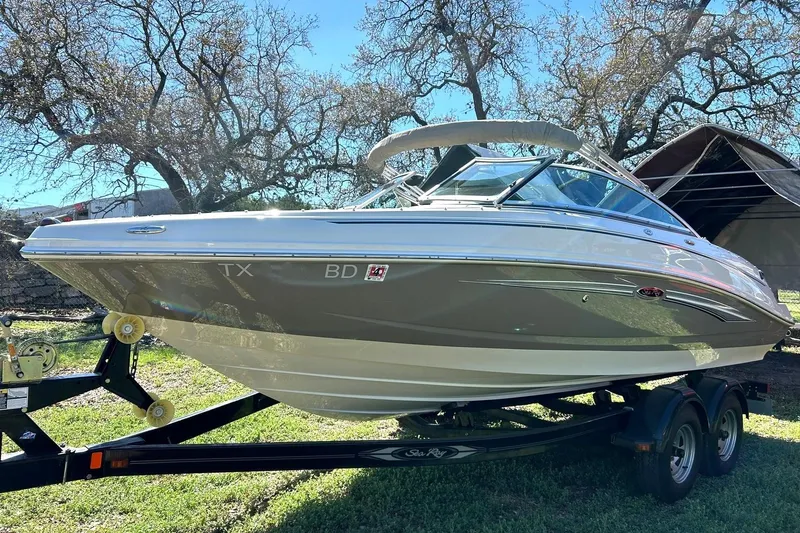 Slide: The Image of 2009 Sea Ray 210 boat on trailer, parked outdoors under trees. - 12