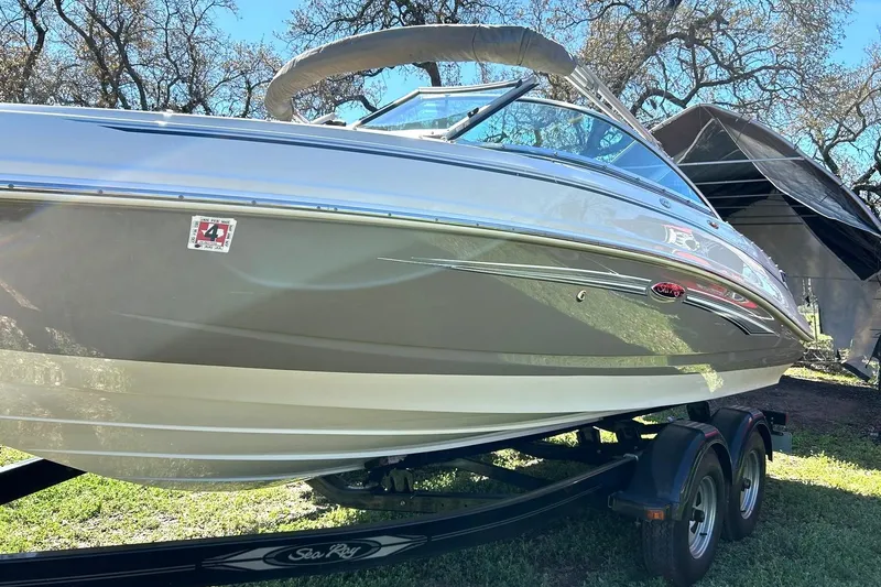 Slide: The Image of 2009 Sea Ray 210 boat on trailer, parked outdoors under trees. - 14