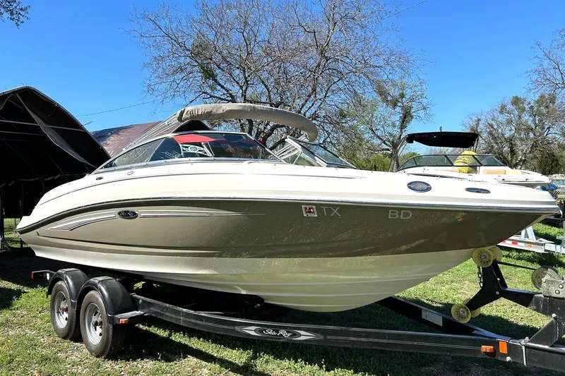 Slide: The Image of 2009 Sea Ray 210 boat on trailer, parked outdoors under clear blue sky. - 6