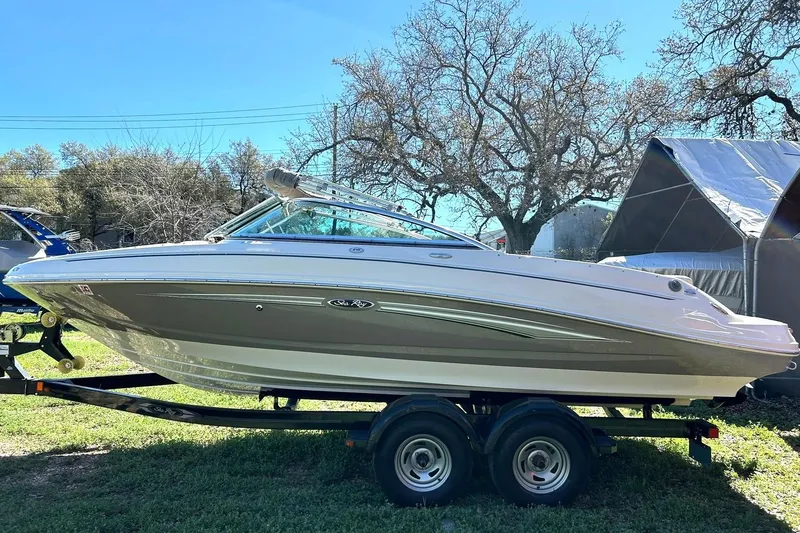 Slide: The Image of 2009 Sea Ray 210 boat on trailer, parked outdoors with trees in background. - 9