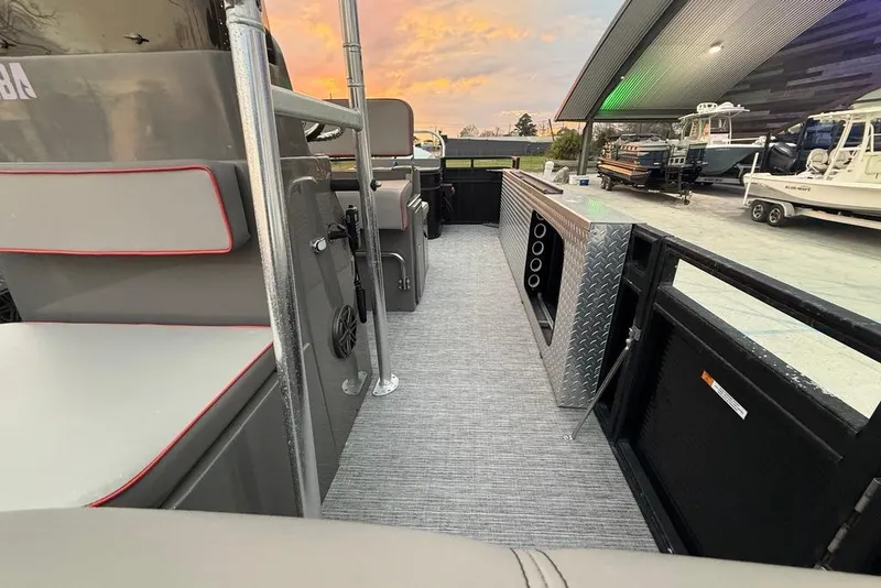 Slide: The Image of 2022 Apex Marine 8524 Pro Fish N Cruise interior with seating and storage, under a sunset sky. - 15