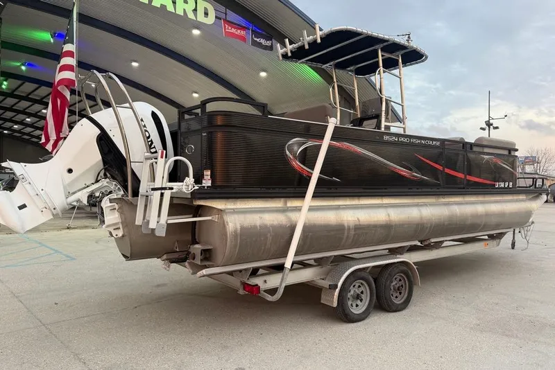 Slide: The Image of 2022 Apex Marine 8524 Pro Fish N Cruise pontoon boat on trailer, parked outside dealership. - 2