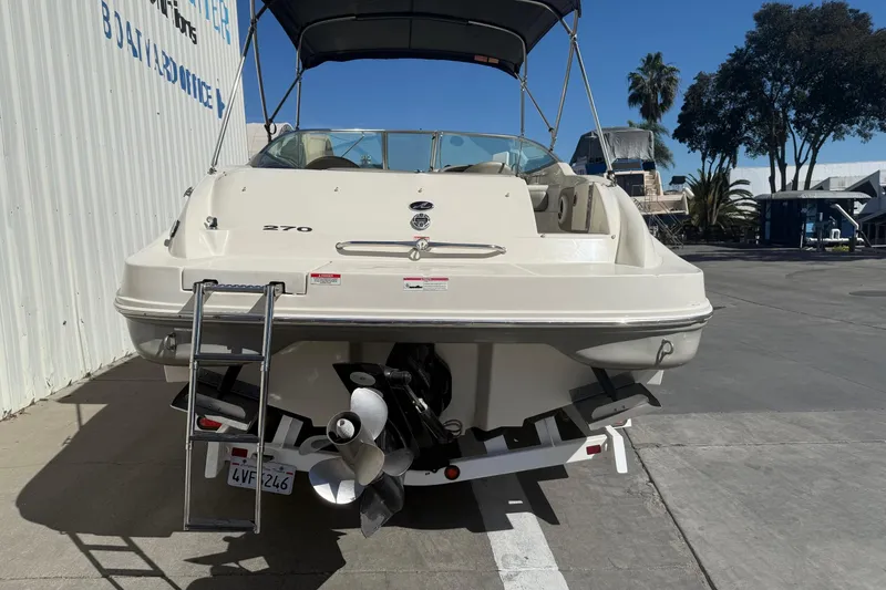 Slide: The Image of 2007 Sea Ray 270 Sundeck boat with ladder, parked outdoors near a building. - 5