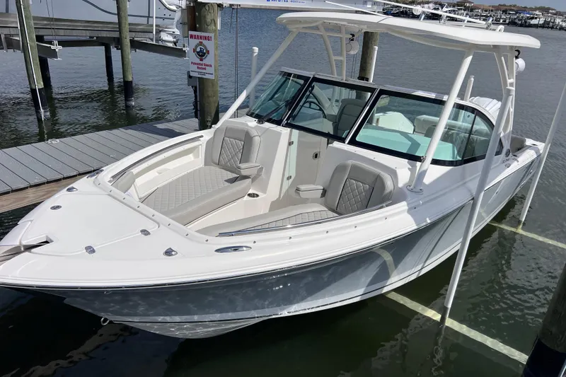 Slide: The Image of 2022 Pursuit DC 246 Dual Console boat docked at marina, featuring sleek design and spacious seating. - 11