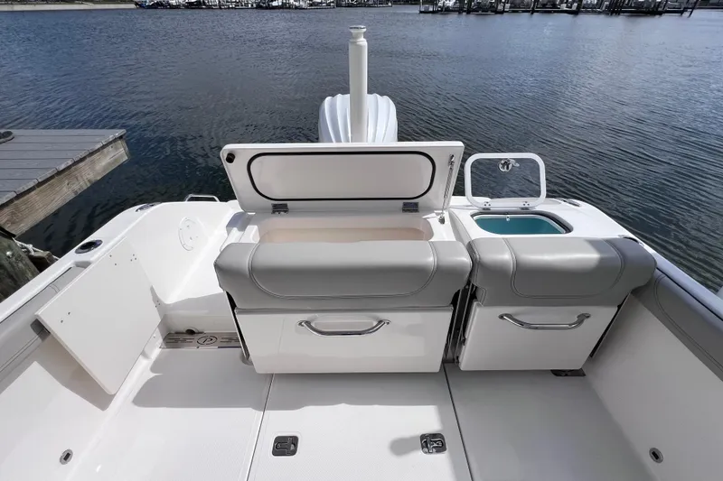 Slide: The Image of 2022 Pursuit DC 246 Dual Console boat interior with open storage compartments by the water. - 21