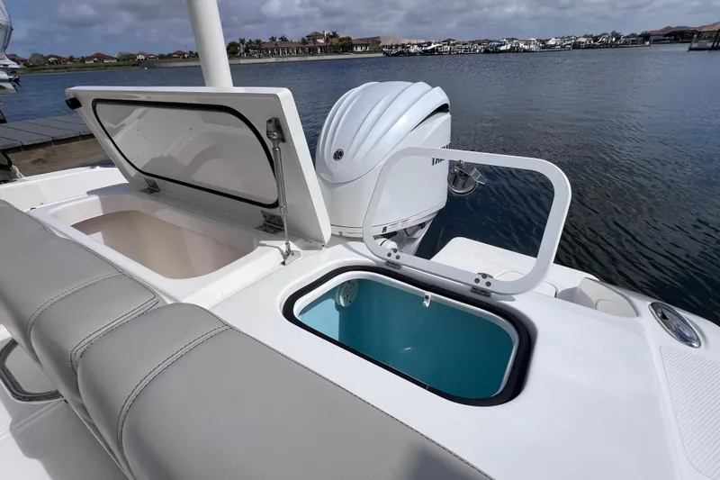 Slide: The Image of 2022 Pursuit DC 246 Dual Console boat with open storage compartments by the water. - 22