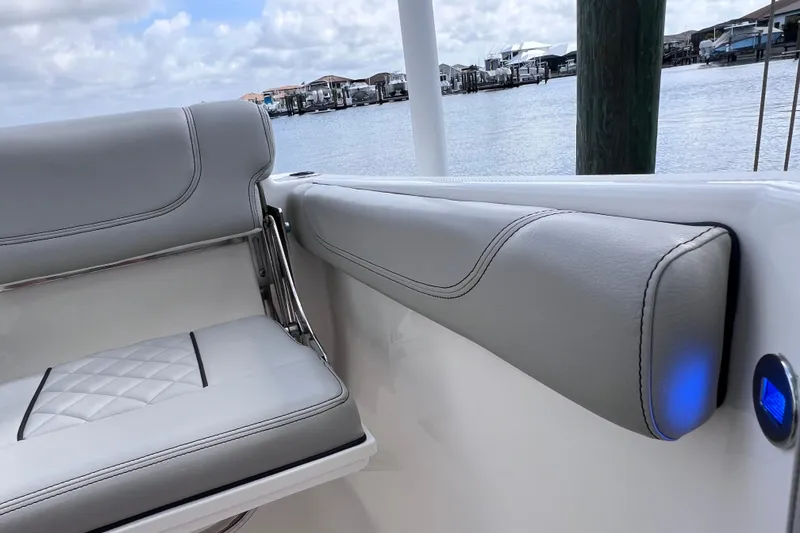Slide: The Image of 2022 Pursuit DC 246 Dual Console boat interior with gray cushioned seating by the water. - 25