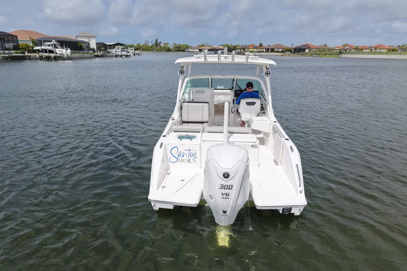 Slide: The Image of 2022 Pursuit DC 246 Dual Console boat on calm water, rear view with outboard motor. - 3