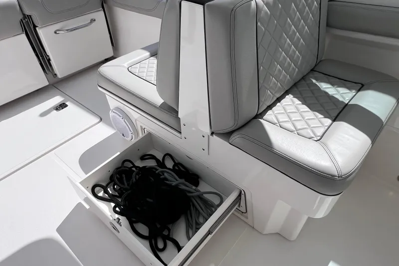 Slide: The Image of 2022 Pursuit DC 246 Dual Console boat interior with storage drawer and cushioned seating. - 33