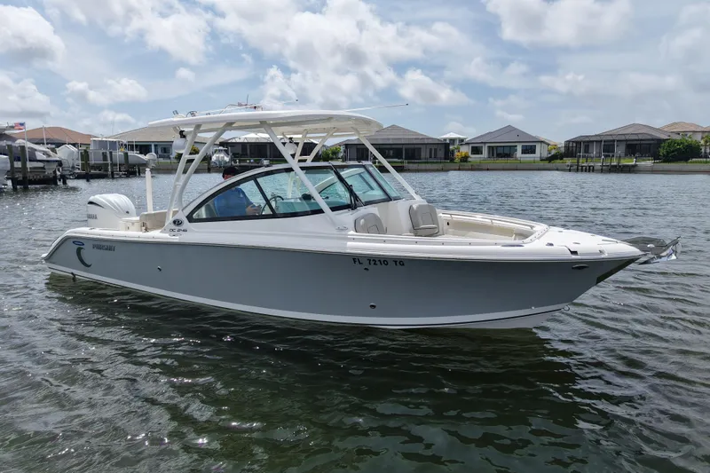 Slide: The Image of 2022 Pursuit DC 246 Dual Console boat on calm water, with houses in the background. - 5