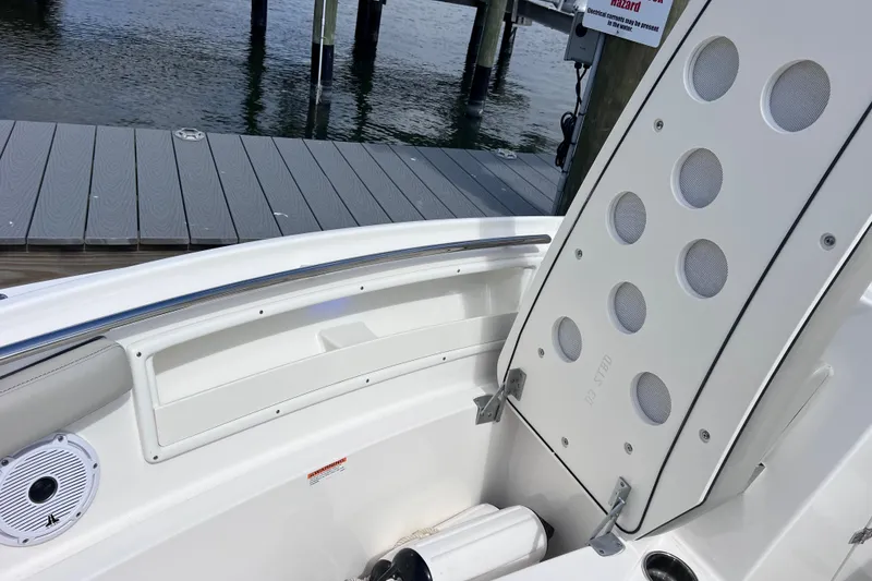 Slide: The Image of 2022 Pursuit DC 246 Dual Console boat interior near dock, showcasing seating and storage. - 56