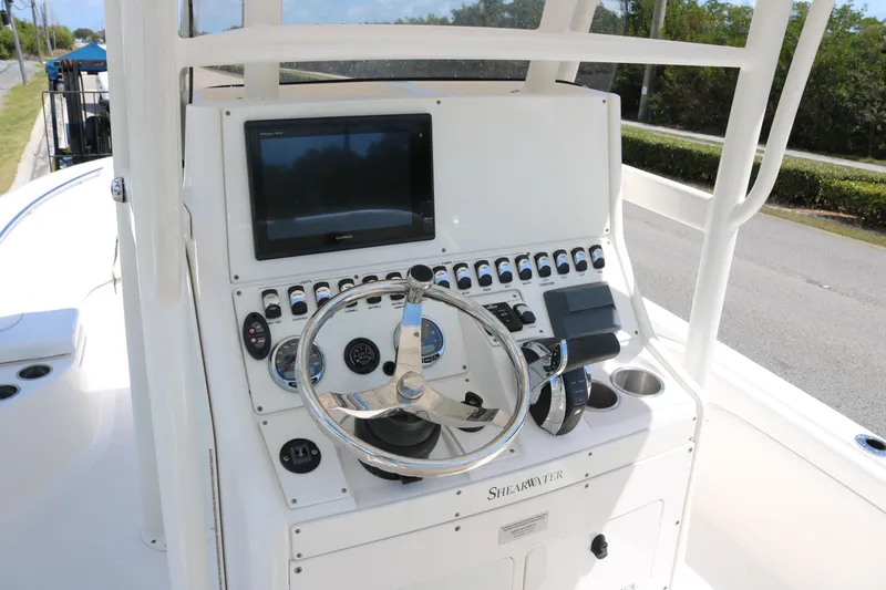 Slide: The Image of 2019 ShearWater 26 Carolina boat console with steering wheel and navigation display. - 11