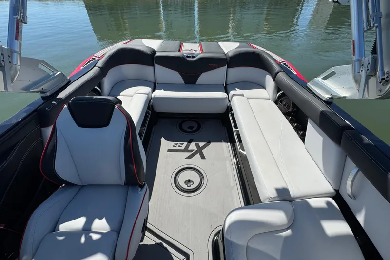 Slide: The Image of 2019 MasterCraft XT22 boat interior with sleek seating and modern design on calm water. - 21