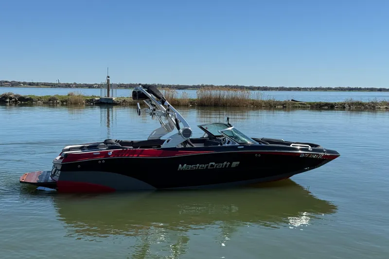 Slide: The Image of 2019 MasterCraft XT22 boat on calm lake with clear blue sky. - 4