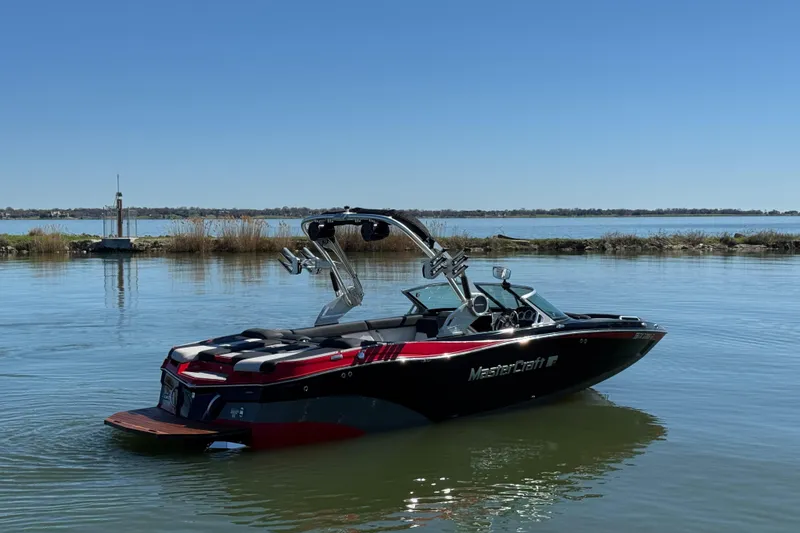 Slide: The Image of 2019 MasterCraft XT22 boat on calm lake with clear blue sky. - 5