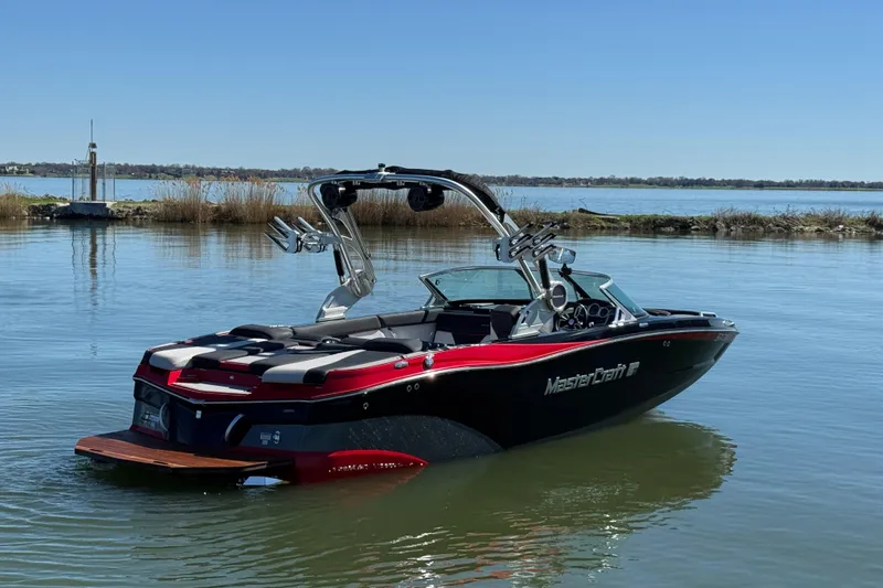 Slide: The Image of 2019 MasterCraft XT22 boat on calm lake with clear blue sky. - 6
