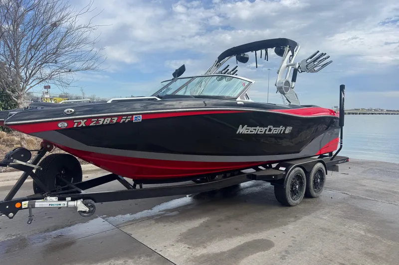 Slide: The Image of 2019 MasterCraft XT22 boat on trailer by the water, black and red design. - 8