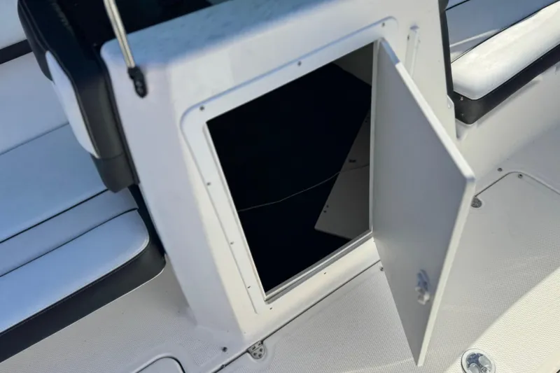 Slide: The Image of Open storage compartment on 2018 Yamaha Boats AR210, featuring sleek white interior design. - 24