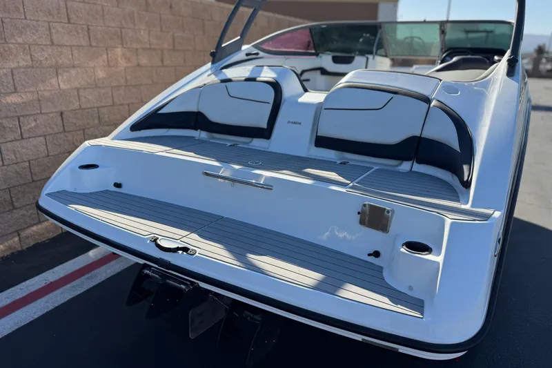 Slide: The Image of 2018 Yamaha Boats AR210, rear view, sleek design, white and black seating, outdoor setting. - 6