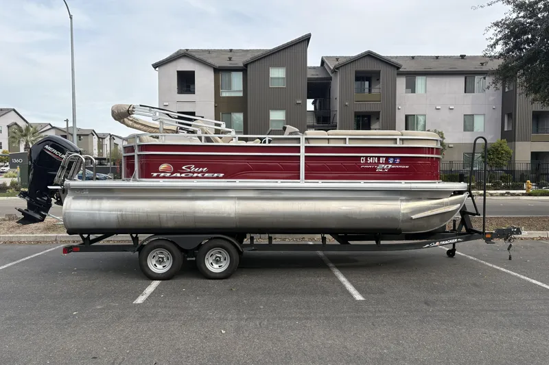 The Image of 2024 Sun Tracker Party Barge 20 DLX pontoon boat on trailer in parking lot. - 0