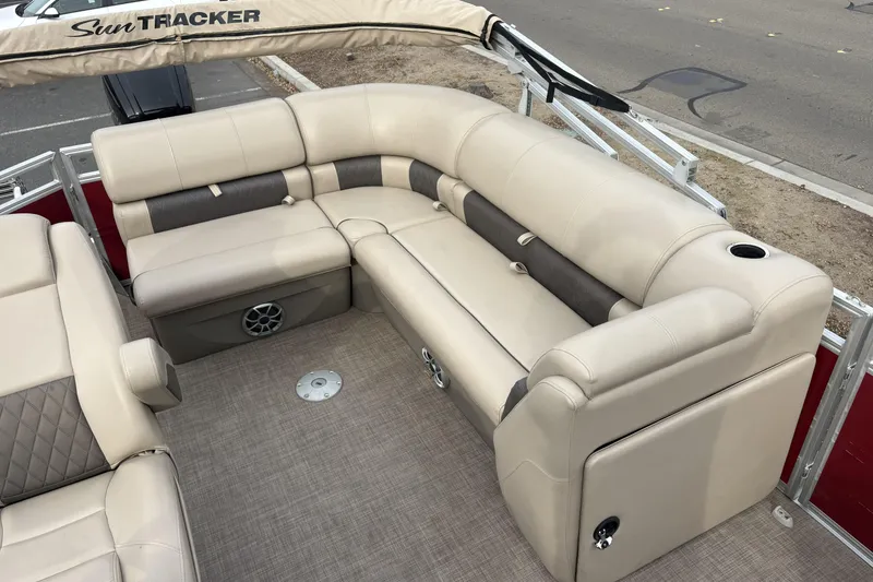 Slide: The Image of 2024 Sun Tracker Party Barge 20 DLX interior with beige seating and cup holders. - 12
