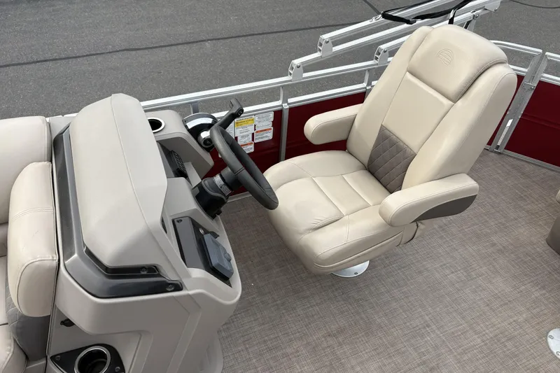 Slide: The Image of 2024 Sun Tracker Party Barge 20 DLX helm with beige captain's chair and steering console. - 13