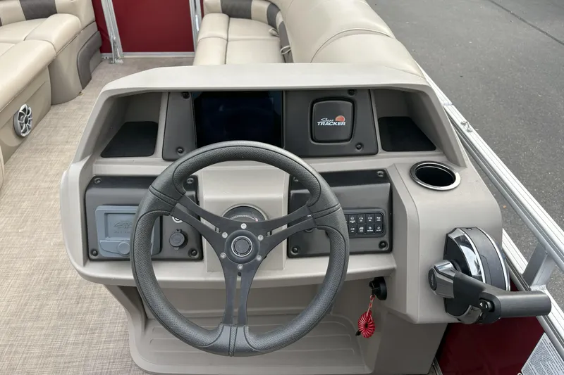 Slide: The Image of 2024 Sun Tracker Party Barge 20 DLX steering console with controls and cup holder. - 16