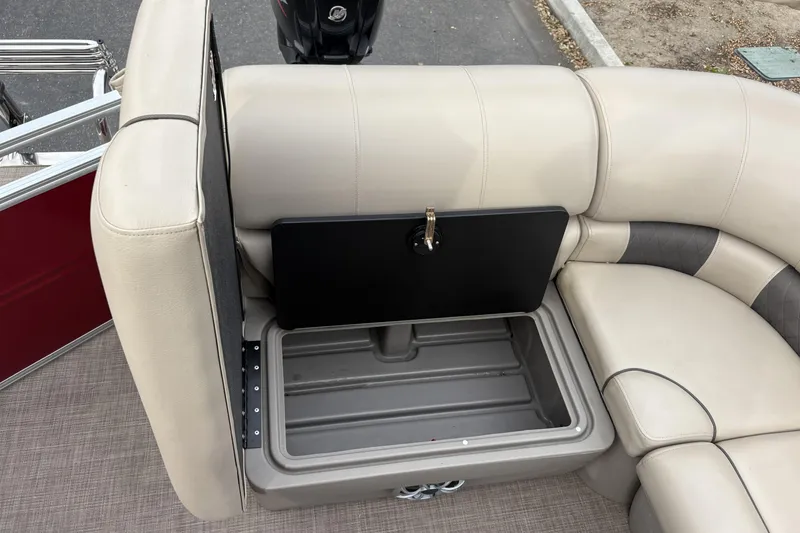 Slide: The Image of 2024 Sun Tracker Party Barge 20 DLX storage compartment with beige seating and open lid. - 19