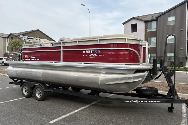 Slide: The Image of 2024 Sun Tracker Party Barge 20 DLX pontoon boat on trailer in parking lot. - 2