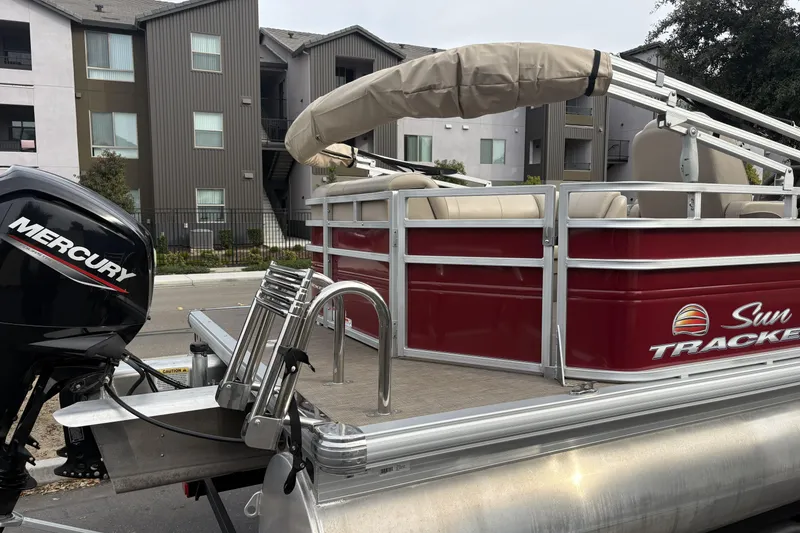 Slide: The Image of 2024 Sun Tracker Party Barge 20 DLX pontoon boat with Mercury engine, parked near apartments. - 4