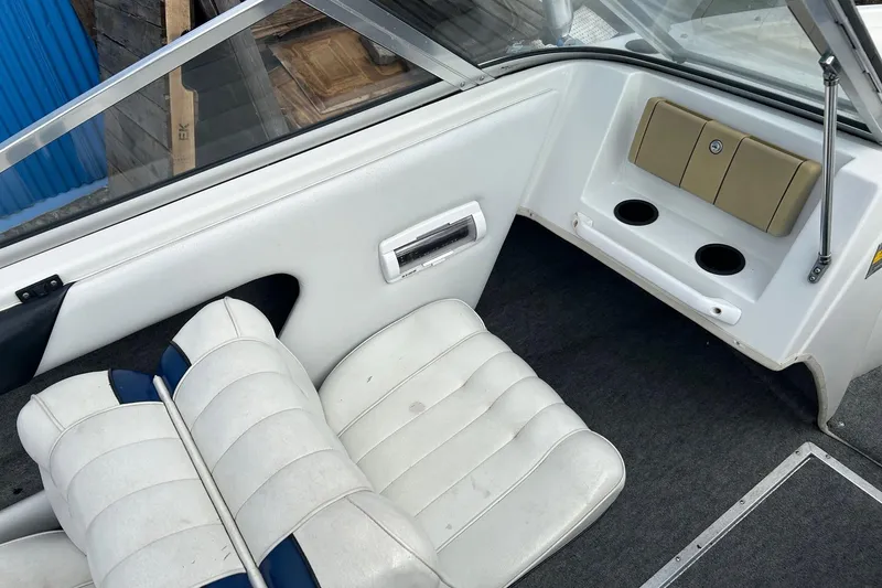 Slide: The Image of Interior of a 1995 Reinell 18 BRXL boat with white seating and cup holders. - 11