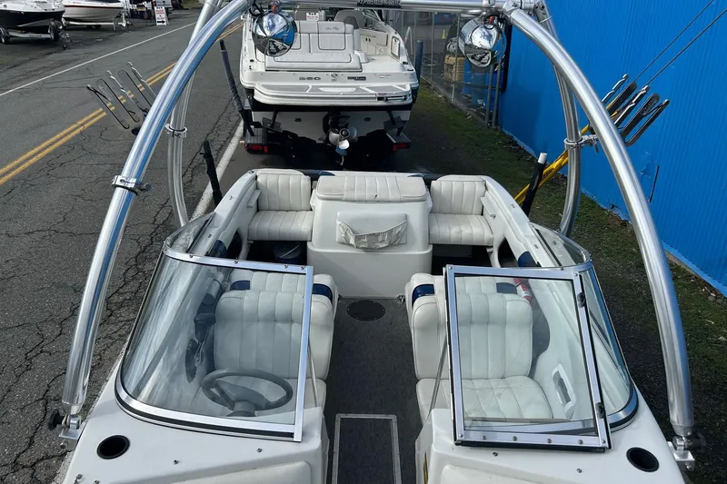 Slide: The Image of 1995 Reinell 18 BRXL boat with white interior and wakeboard tower, parked near a blue wall. - 13