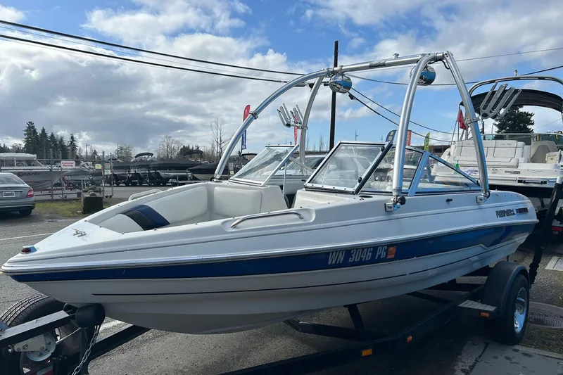 Slide: The Image of 1995 Reinell 18 BRXL boat on trailer, white with blue accents, parked outdoors. - 3